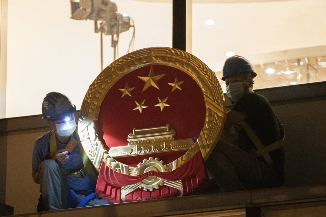 Workers fix the national emblem outside Hong Kong’s Metropark Hotel in Causeway Bay on July 8, now the temporary home of the Office for Safeguarding National Security. Photo: Robert Ng