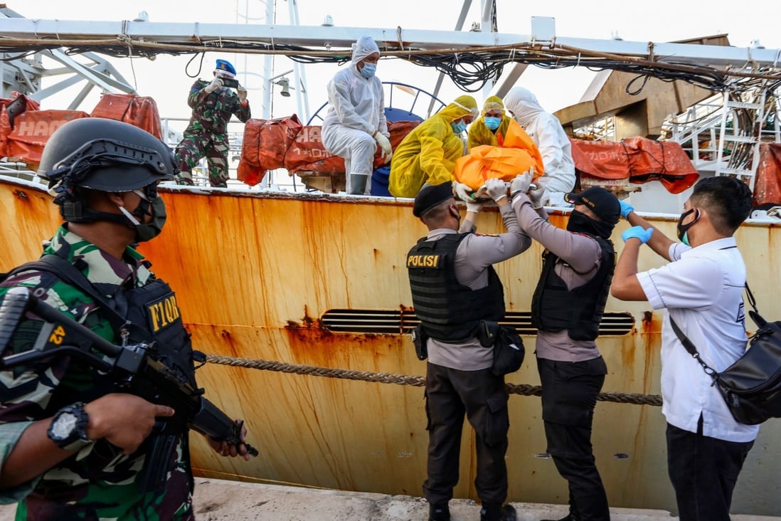 Police remove the body of an Indonesian crew member on a Chinese fishing boat after he was killed in Batam. Photo: AFP