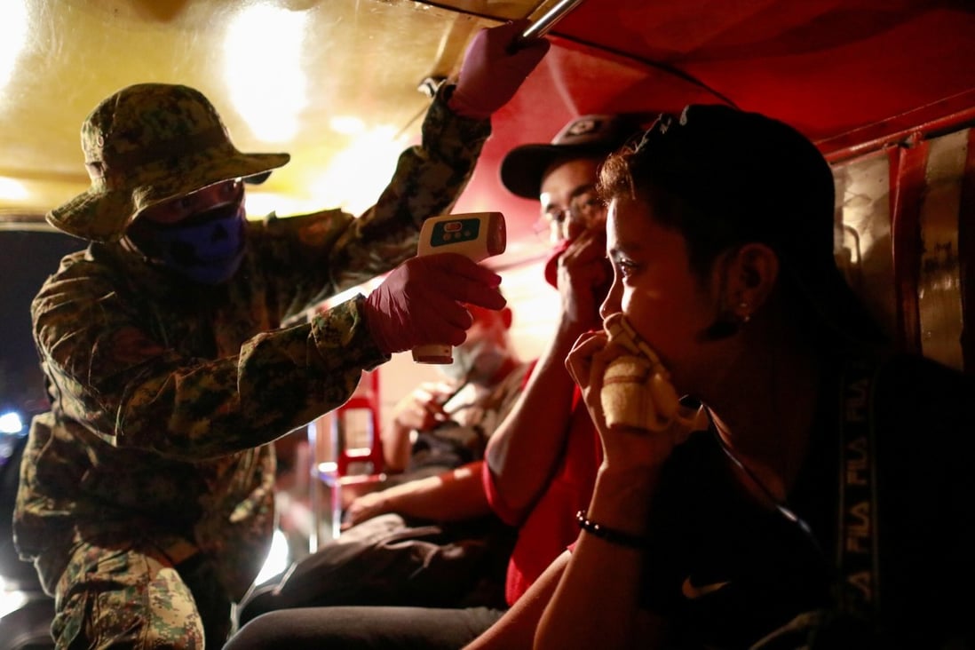 A police officer takes a commuter’s body temperature at a checkpoint in Quezon City, the Philippines. Photo: Reuters