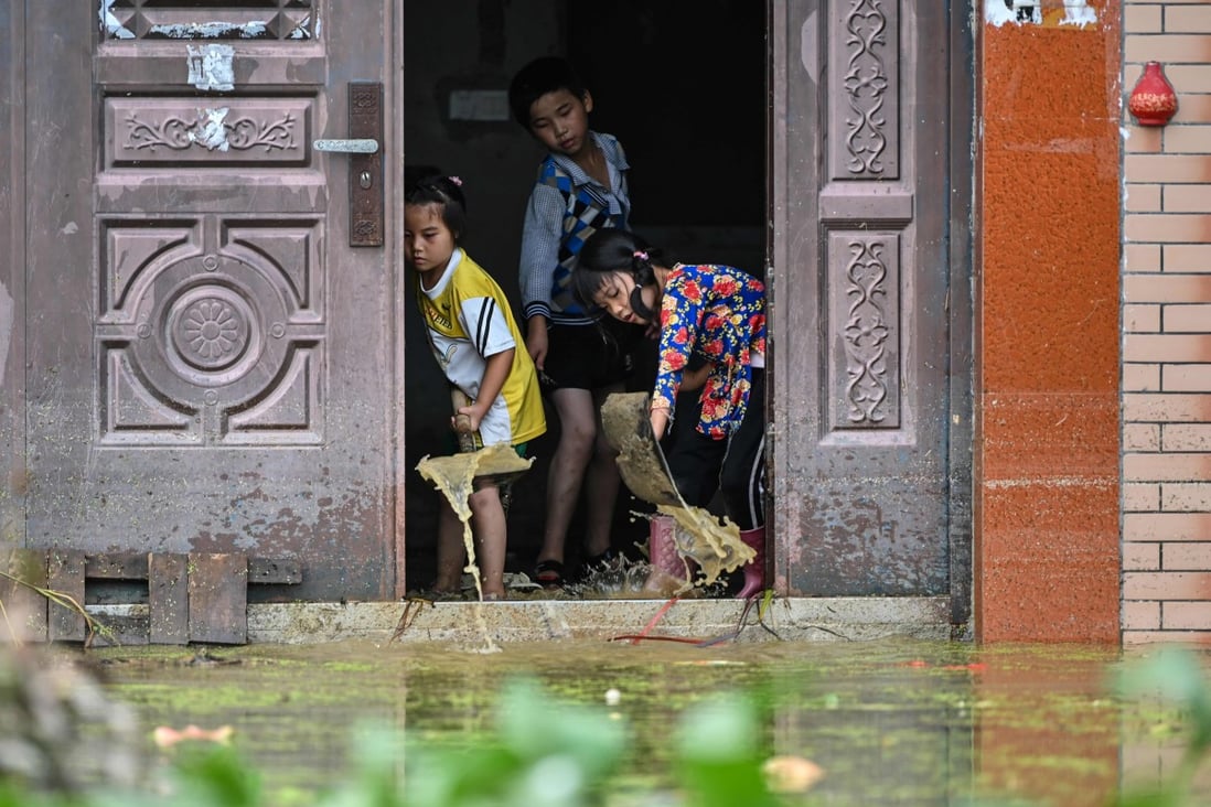Children remove water from inside their house in Longkou village due to torrential rains in China's central Jiangxi province on Thursday. Photo: AFP
