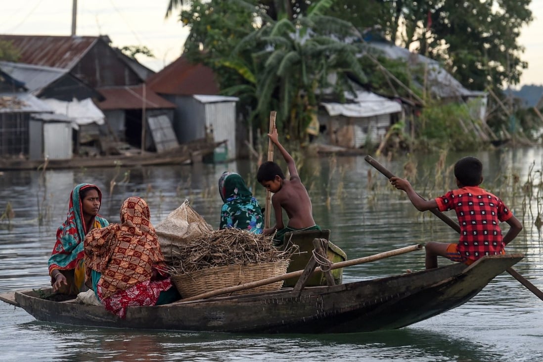 Women and children use a boat to make their way through floodwaters in Sunamganj in Bangladesh. Photo: AFP