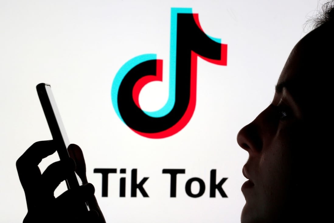 A woman holds a smartphone as a Tik Tok logo is displayed behind her. Since it was created in 2017, TikTok has become a staple of internet culture and social interaction for teenagers. Photo: Reuters