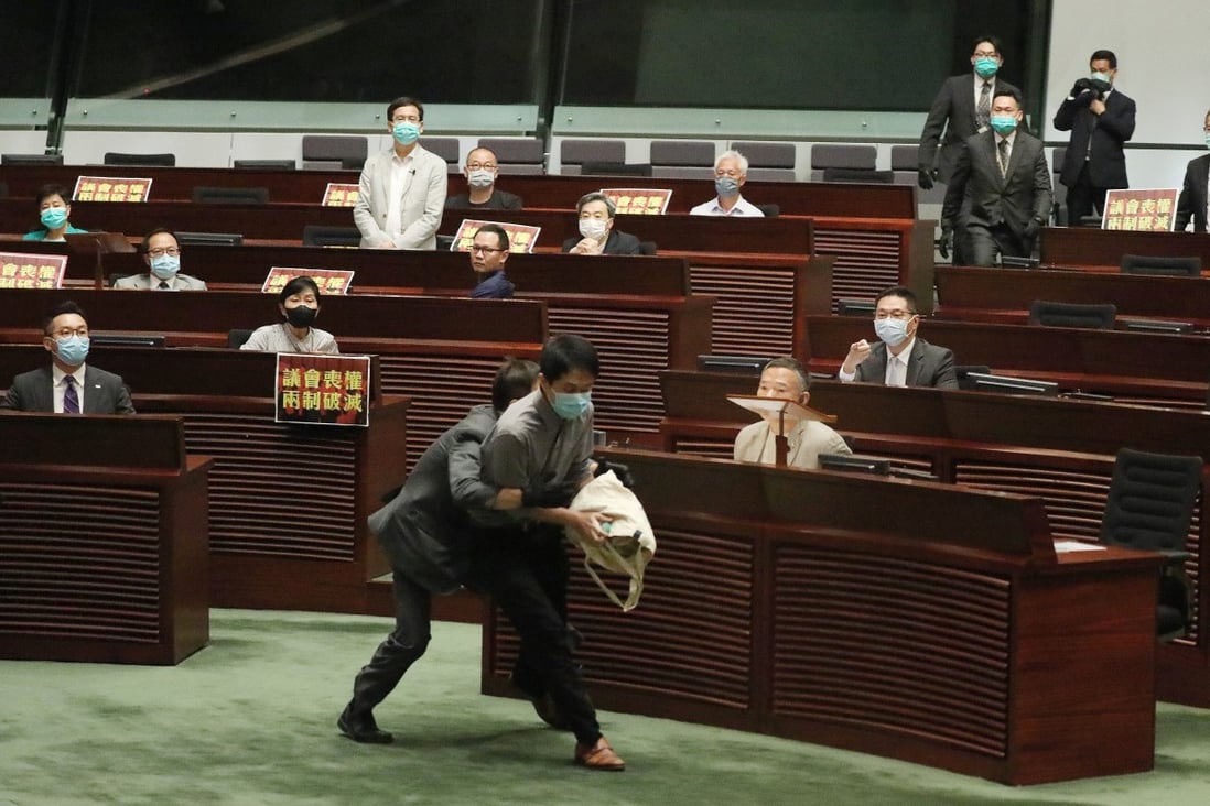 A Legislative Council security guard attempts to tackle Democratic Party legislator Ted Hui Chi-fung, who is trying to hurl a container of foul-smelling rotten plants on May 28. Photo: Nora Tam