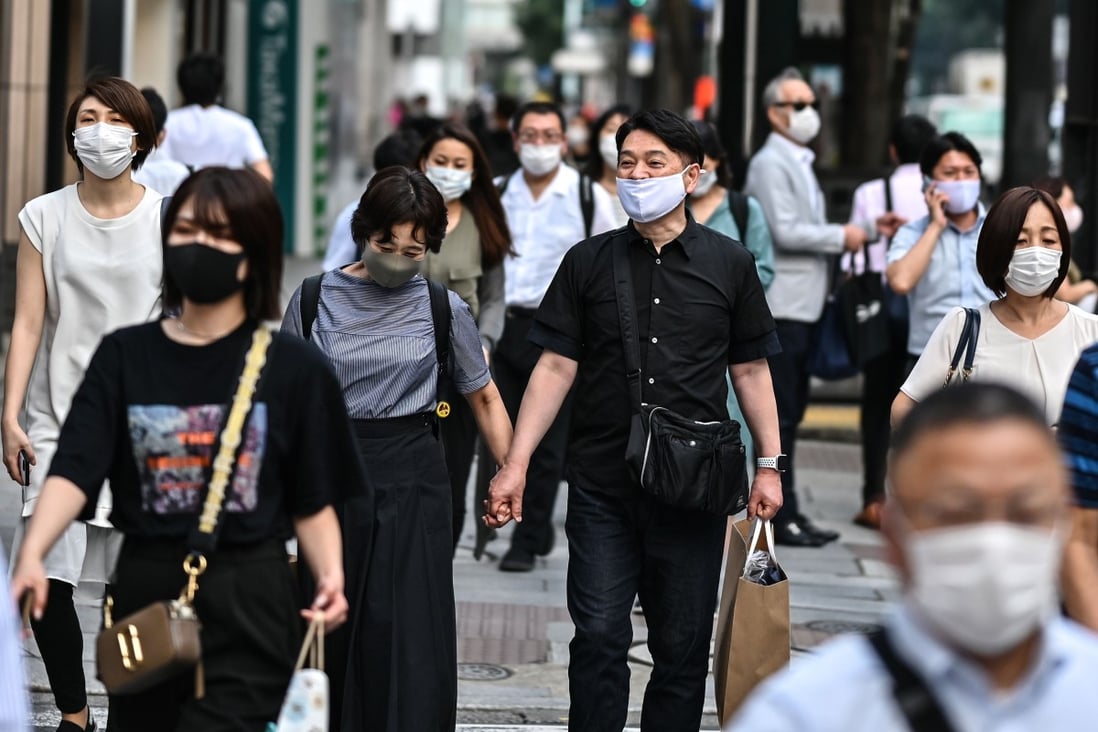 People wearing face masks walk in a street in Tokyo on July 20, as Japan’s death toll eclipsed 1,000, and 168 new cases were recorded in the capital. Photo: AFP