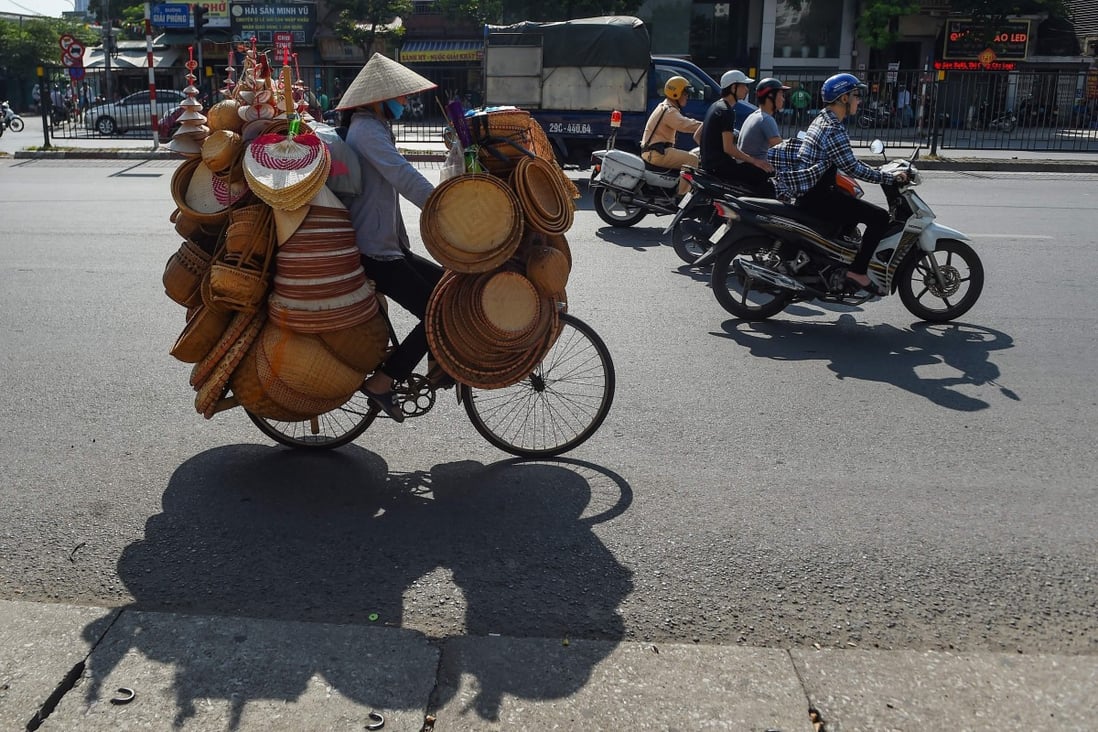 A street vendor wears a face mask as she rides a bicycle with her housewares in Hanoi. Vietnam has reported its first local coronavirus transmission in three months. Photo: AFP