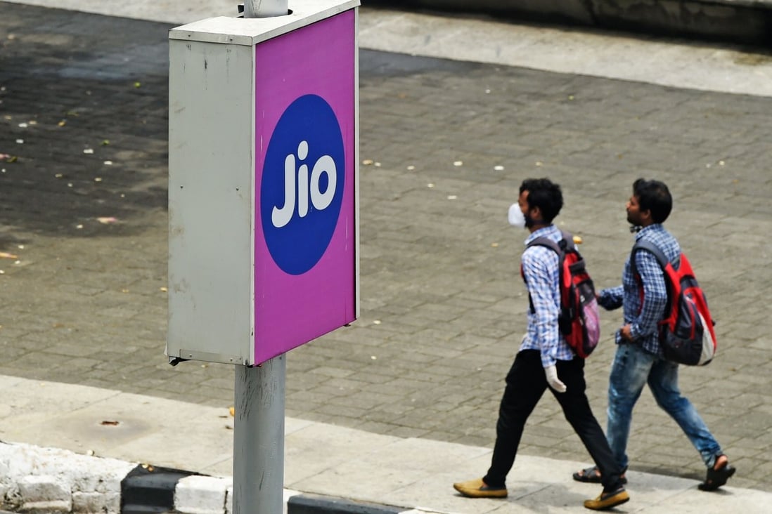 Commuters walk past an advertising board of Reliance Jio, a digital platform owned by Indian businessman Mukesh Ambani's Reliance Industries, in Mumbai on June 19, 2020. Photo: AFP