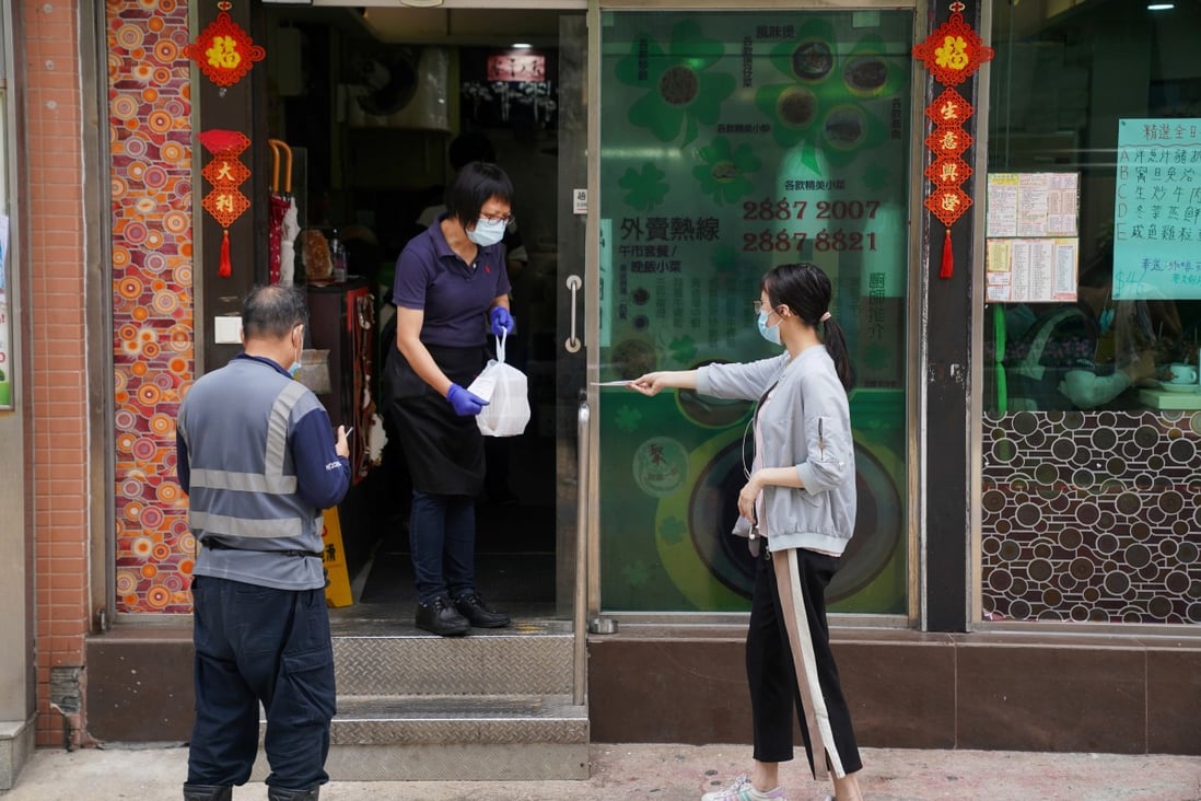 A staff member wearing a face mask hands takeaway food to a customer outside a restaurant in Hong Kong. Photo: Reuters