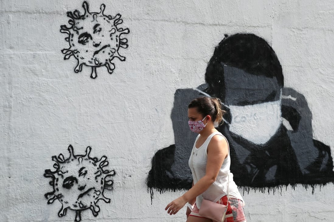 A woman walks past by a graffiti depicting Brazilian President Jair Bolsonaro and viruses in Rio de Janeiro. Photo: Reuters