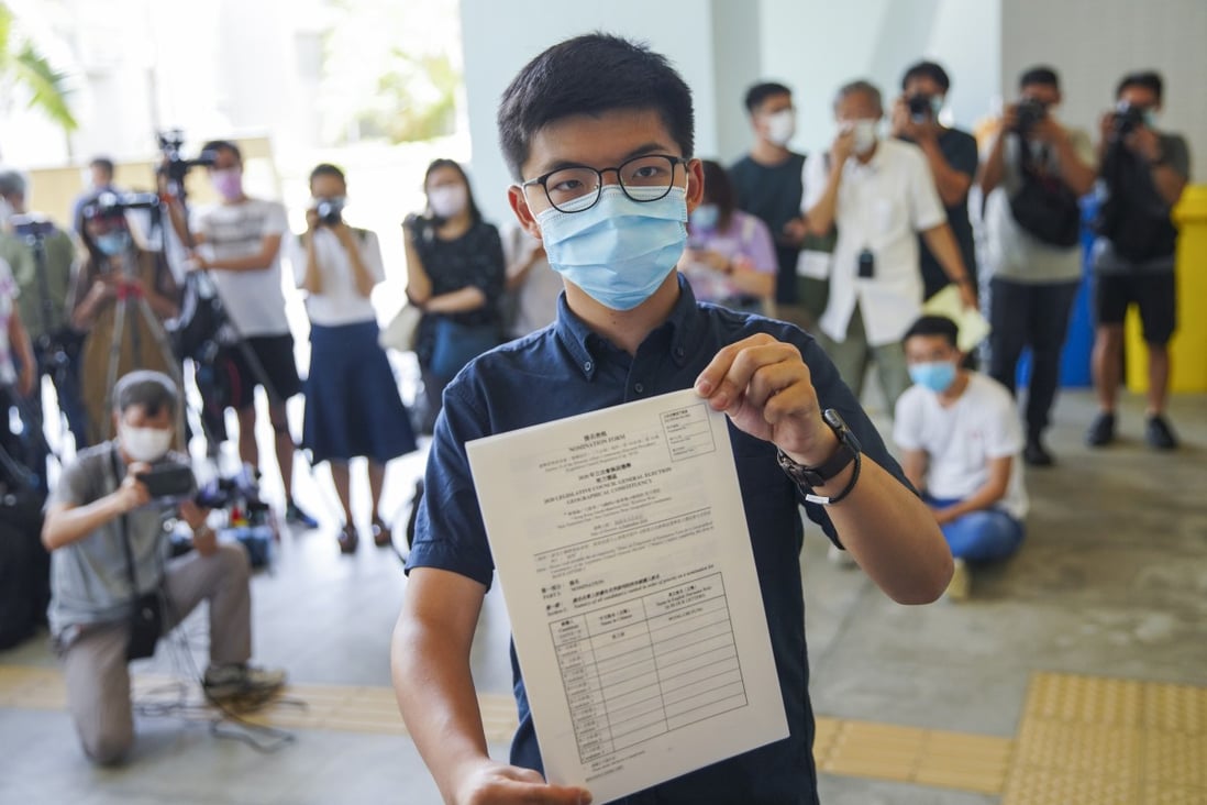 Activist Joshua Wong poses with his nomination papers as he files for his candidacy in the Legislative Council elections on July 20. Wong is one of a dozen opposition candidates who have been disqualified from running in the upcoming election. Photo: Winson Wong