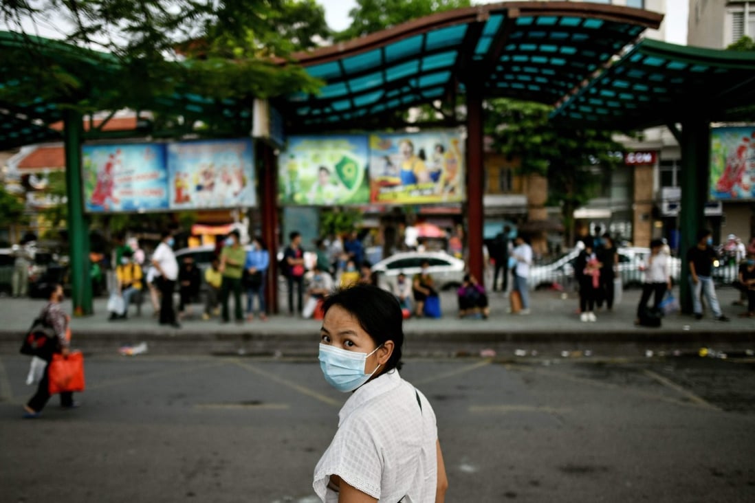 A woman wearing a face mask waits at a bus stop in Hanoi on July 29. Photo: AFP