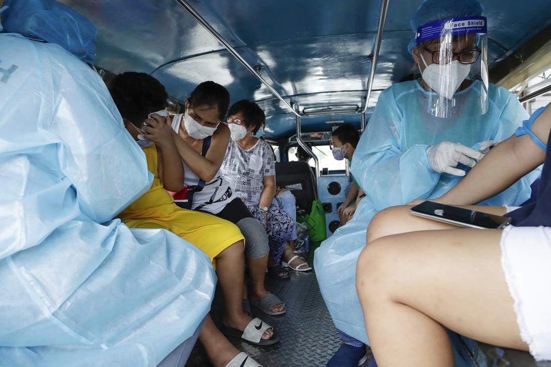 Health workers collect blood samples inside a jeepney bus at a free Covid-19 drive-thru testing facility in Manila. Photo: AP