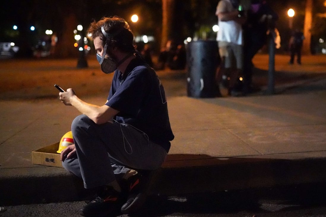A man checks his phone during the first night of protests without federal intervention in weeks in front of the Mark O Hatfield US Courthouse in Portland, Oregon. Photo: AFP