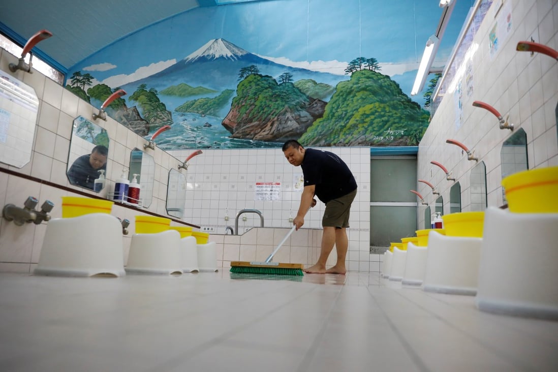 Takuya Shimbo, the third-generation owner of public bathhouse Daikoku-yu, cleans the floor before its daily opening amid the coronavirus disease pandemic in Tokyo. Photo: Reuters