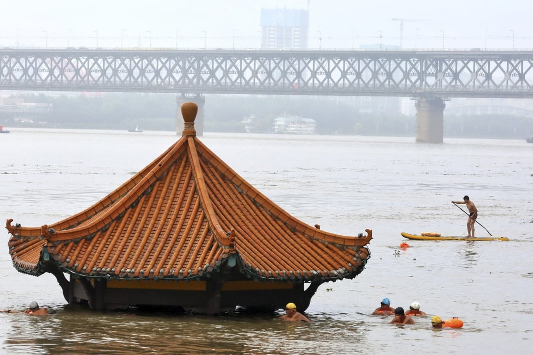 Residents swim past a riverside pavilion submerged by the flooded Yangtze in Wuhan. Photo: AP