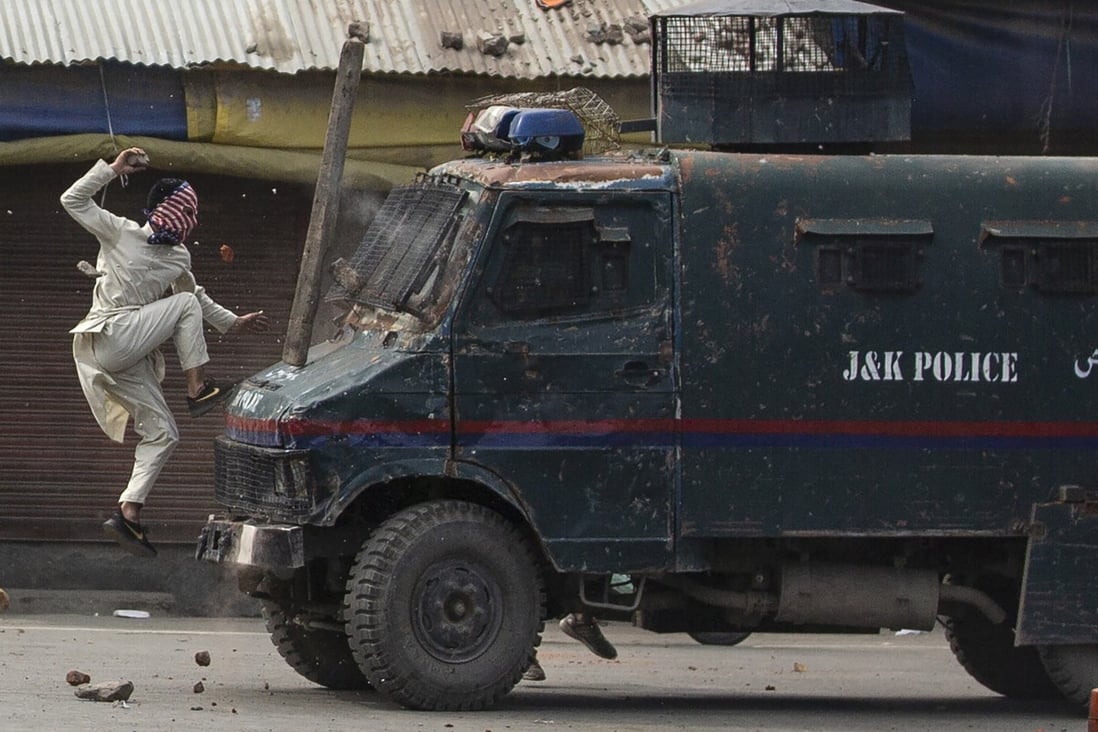 A masked Kashmiri protester jumps on the bonnet of an armoured Indian police vehicle during a May 2019 demonstration in Srinagar. Photo: AP
