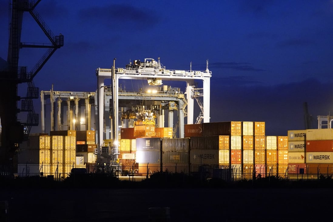 Containers sit next to gantry cranes at dusk at a shipping terminal in Yokohama, Japan in July. Photo: Bloomberg