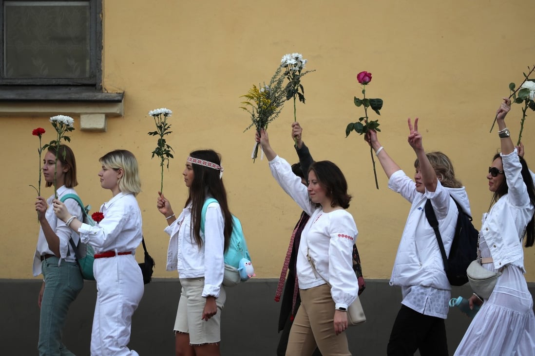 Women hold flowers aloft during a rally on Thursday in Minsk in support of protesters detained and injured in the aftermath of Sunday’s disputed presidential election. Photo: EPA