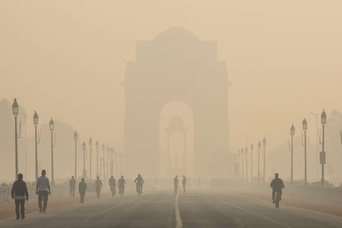 Pedestrians walk along New Delhi’s Rajpath boulevard in November 2019 as the India Gate monument stands shrouded in smog. Photo: Bloomberg