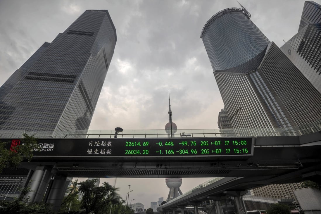 People walk over a pedestrian bridge that features a monitor for stock exchange values in Shanghai. Photo: EPA-EFE