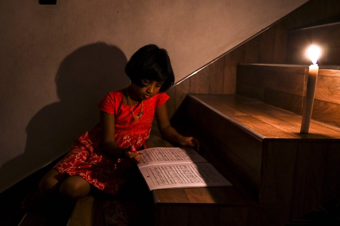 A girl reads a book in candlelight in Colombo. File photo: AFP
