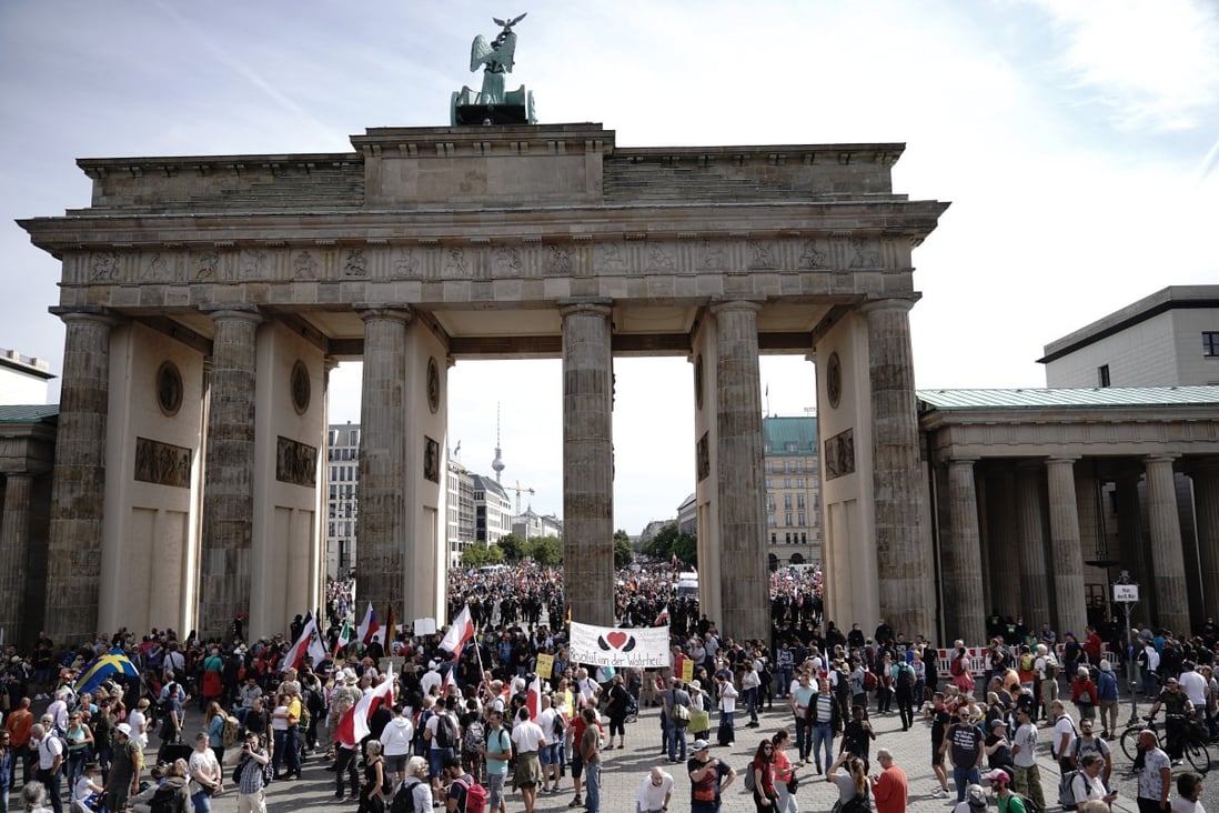 People hold banners and flags during a rally against the coronavirus measures in Berlin. Photo: DPA