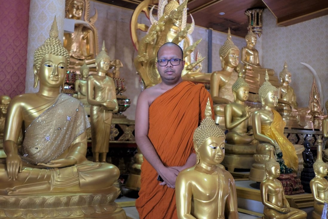 Phra Maha Paiwan Warawanno, a Buddhist monk in Thailand, stands among golden Buddha statues at Wat Soi Thong temple in Bangkok. He insists that the Buddha does not grant wishes like a genie from a lamp. Photo: Tibor Krausz