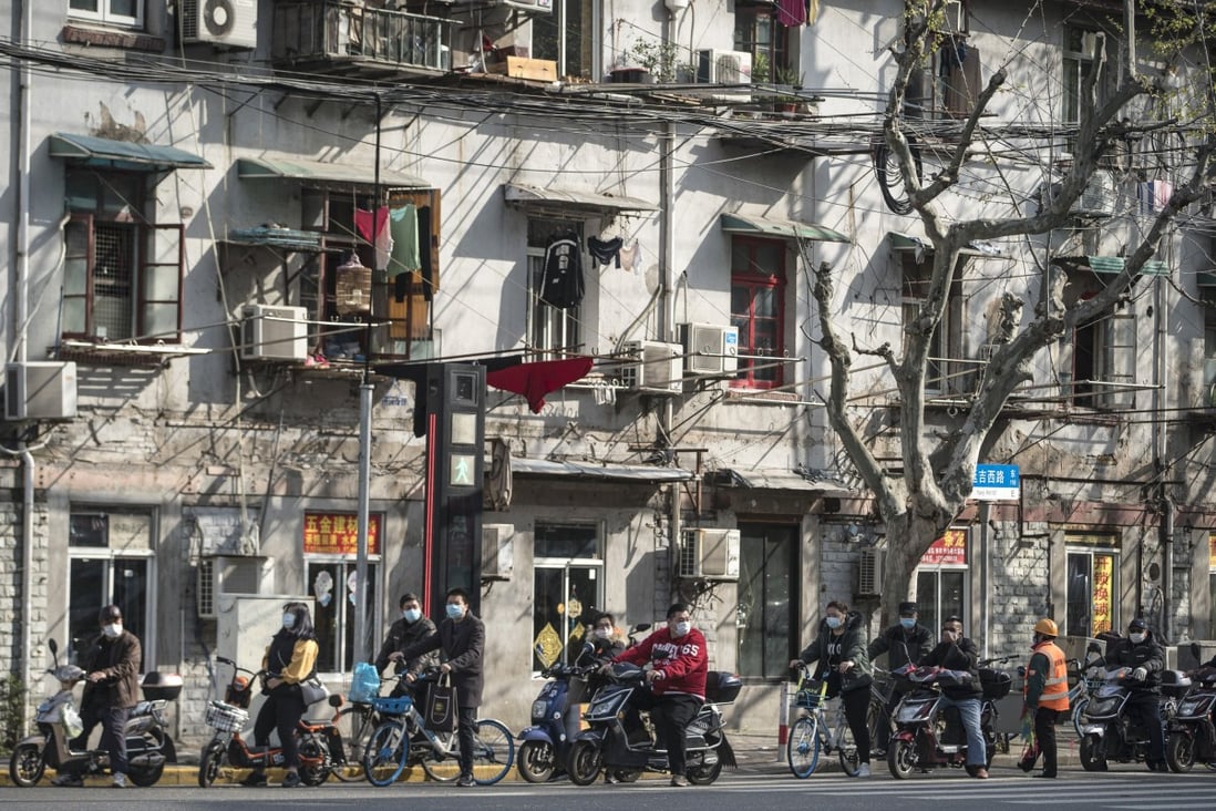 Moped riders and cyclists wearing masks wait at a traffic light in Shanghai on April 2. Photo: Bloomberg