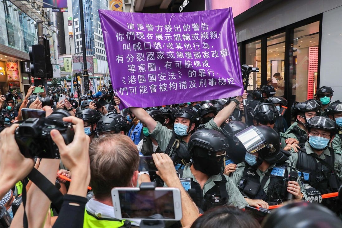 A police officer raises a flag warning protesters they could be in violation of the new national security law in Causeway Bay on July 1. Photo: Sam Tsang