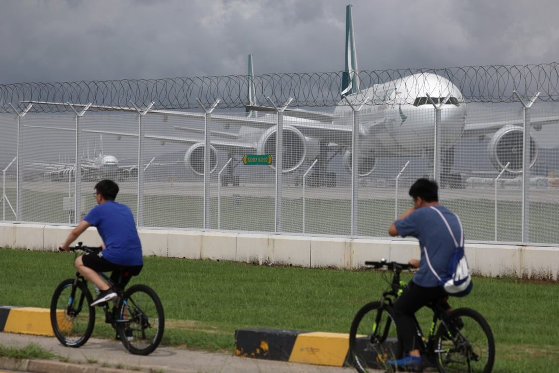 Two cyclists pass a line of grounded Cathay Pacific aircraft at Hong Kong International Airport. Photo: Sam Tsang