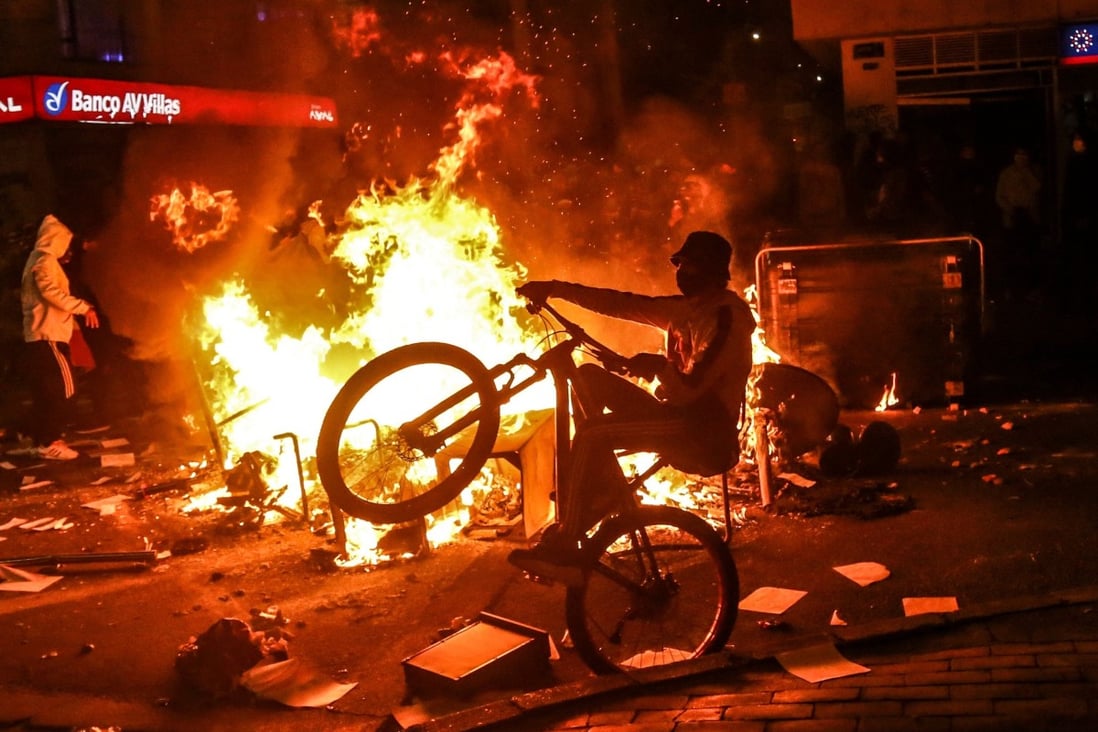 A demonstrator rides a bike at a barricade set on fire during clashes with riot police in Bogota on Thursday. Photo: AFP