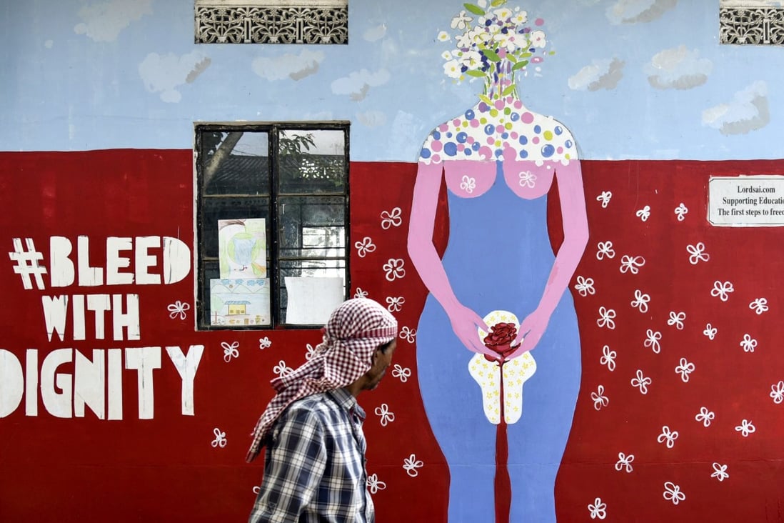 A man walks past a school wall painting about female menstruation in Guwahati, India. Photo: AFP