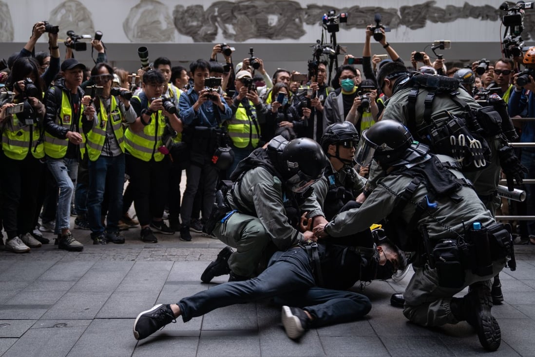 Press photographers surround Hong Kong riot police as they detain a protester at an anti-government rally last year. Photo: DPA
