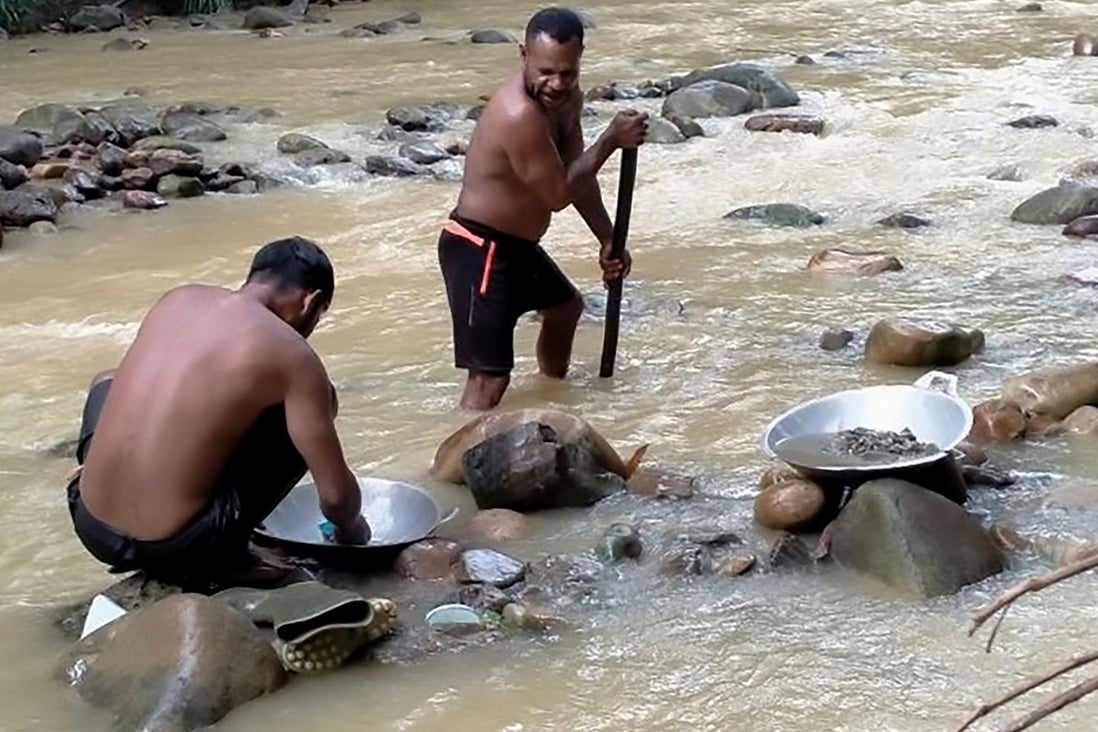 Two miners pan for gold in a river near Korowai, Papua province, Indonesia, despite the risk of arrest and health hazards. Photo: AFP