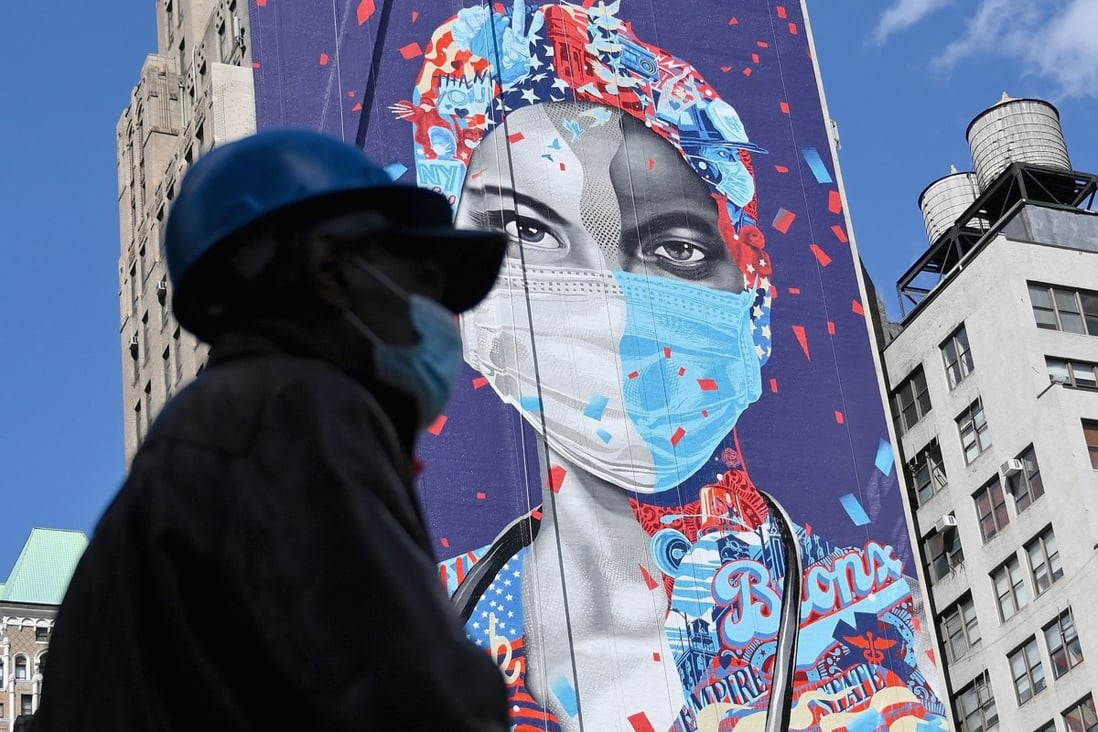 A person wearing a face mask walks past a mural on a building in New York in May. Photo: AFP