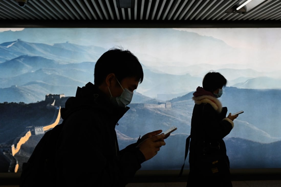 A man and a woman wearing face masks use their mobile phone as they walk in a subway station in Beijing on March 11. Picture: AFP