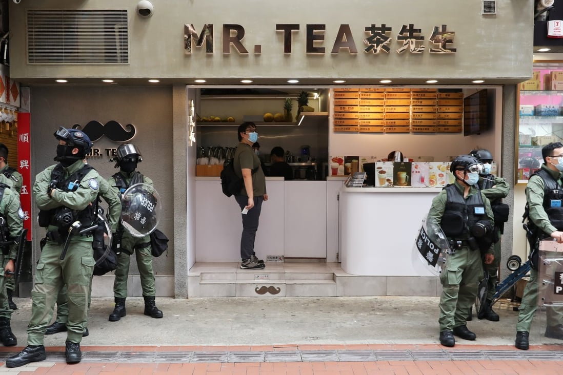 A man orders a drink at a tea shop as police officers stand outside in Causeway Bay on Thursday. Photo: Nora Tam