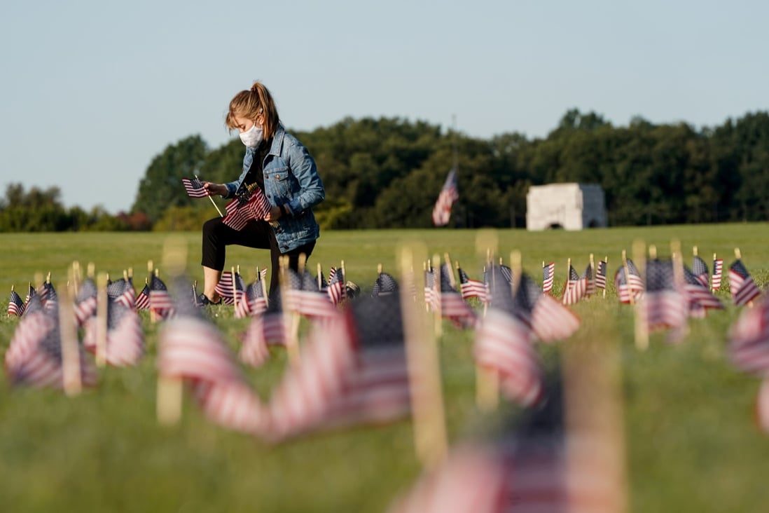 A volunteer places US flags at on the National Mall in Washington, representing some of the 200,000 lives lost during the coronavirus pandemic. Photo: Reuters