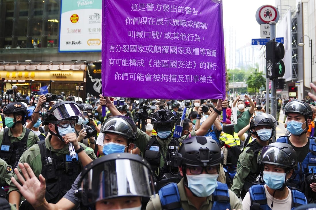 Police hold up a flag warning against breaches to the national security law in Causeway Bay on Thursday. Photo: Sam Tsang