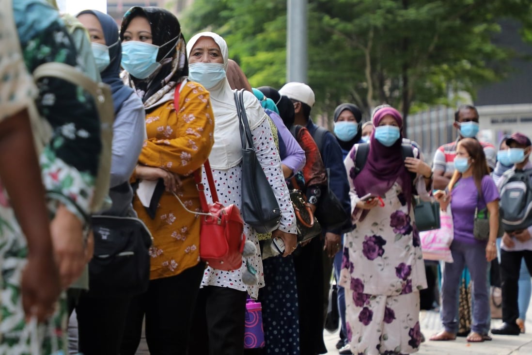 Malaysians line up at a bus stop in Kuala Lumpur. At least two politicians have tested positive as people took to social media to lambast them for violating social distancing protocols and refusing to self-isolate. Photo: Reuters