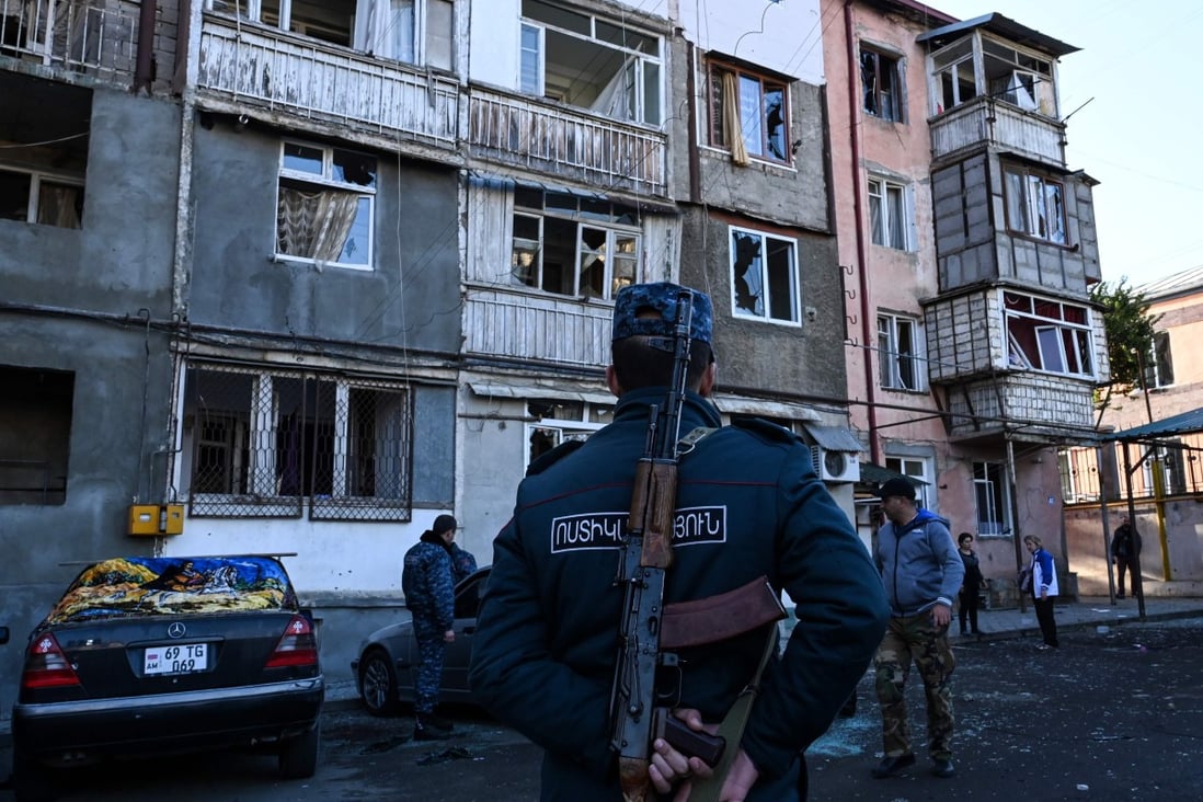 A police officer stands in front of a residential building that was supposedly damaged by shelling in Nagorno-Karabakh’s main city of Stepanakert. Photo: AFP