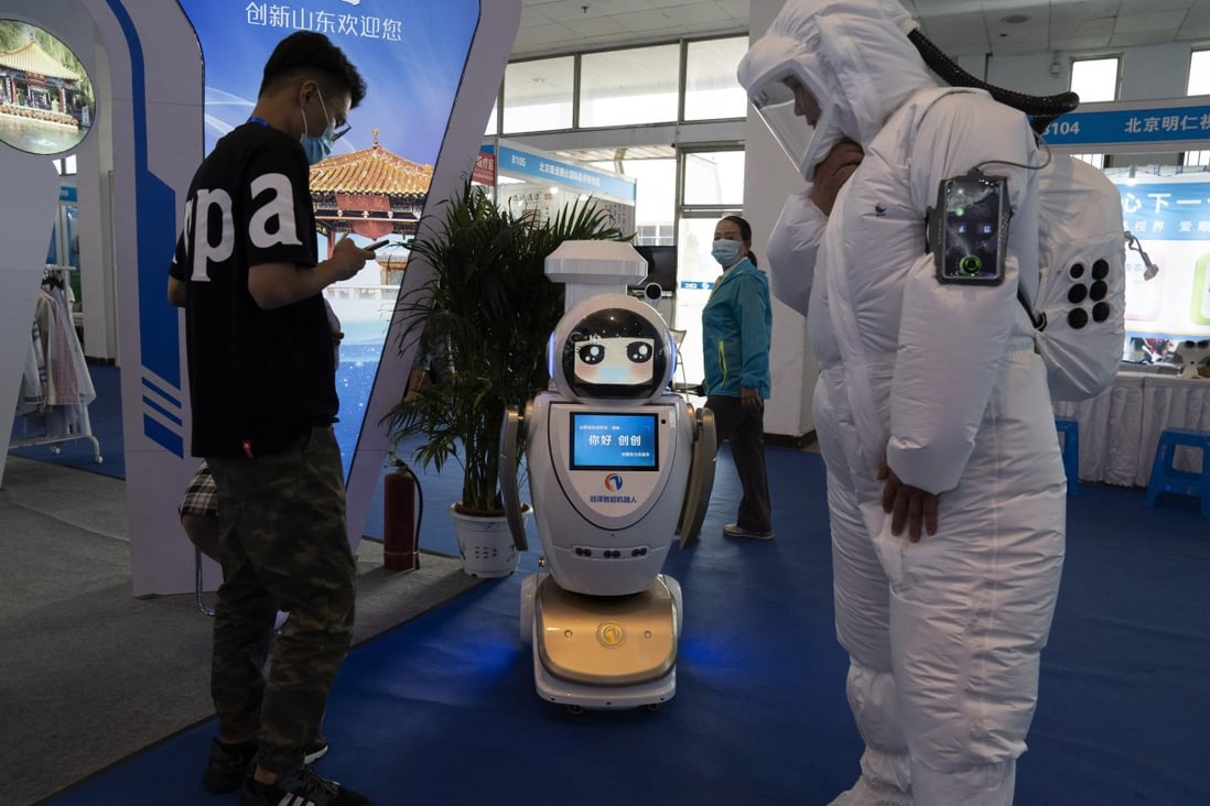 A promoter dressed to look like an astronaut walks past a robot at the China Beijing International High Tech Expo in Beijing, China on Thursday, Sept. 17, 2020. Photo: AP