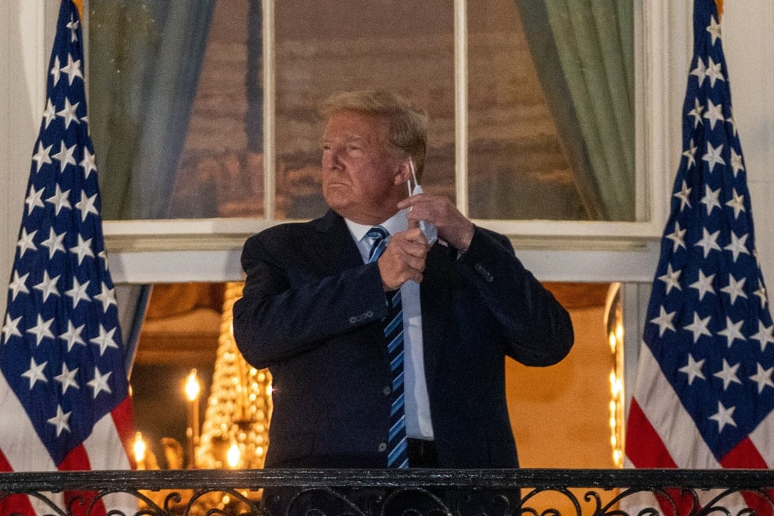 US President Donald Trump removes his protective mask at the White House , after his release from hospital. Photo: Bloomberg