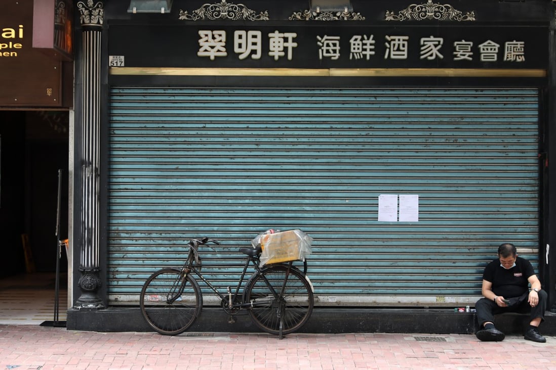 A man sits with his face mask down outside a closed restaurant in Causeway Bay amid the third wave of coronavirus infections. Photo: Nora Tam