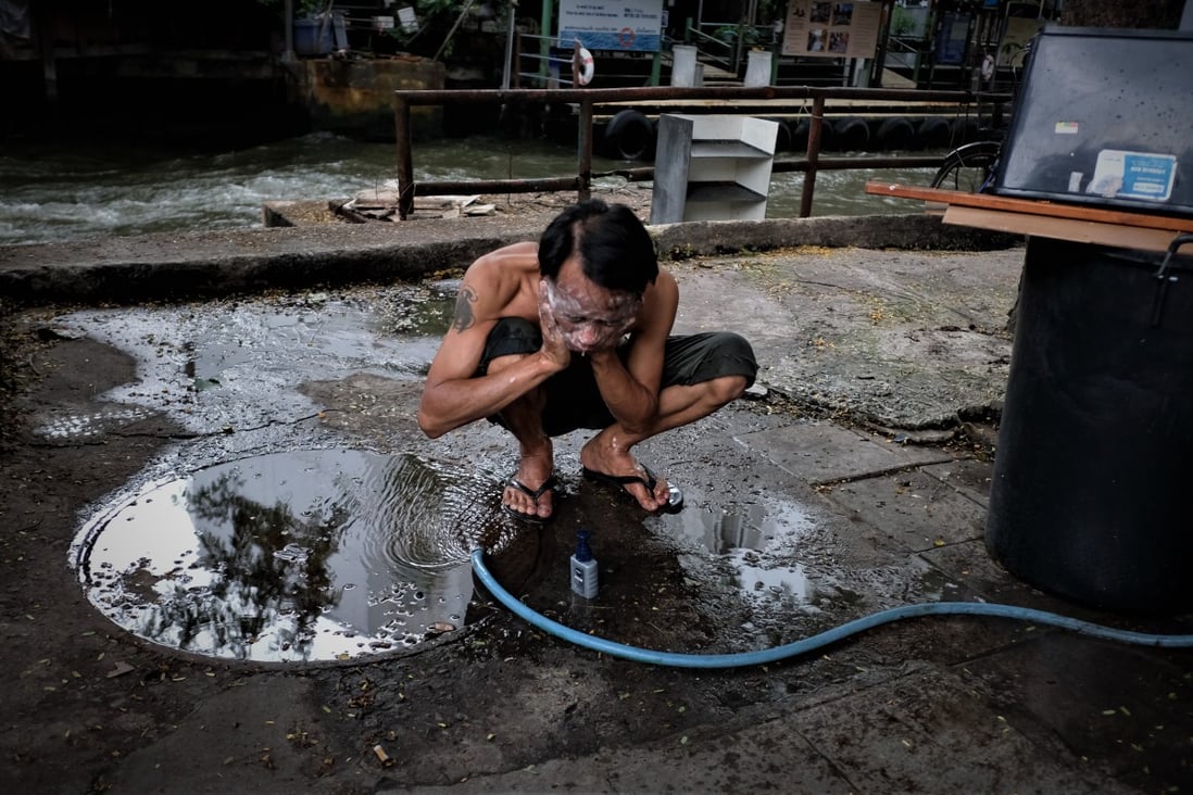 A man washes his face with a hose on the street in Baan Khrua, a shanty town in the centre of Bangkok in the shadow of upscale shopping malls, hotels and condominiums – built where orchards once stood. Photo: Tibor Krausz