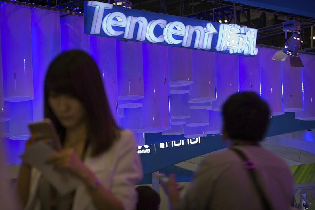 A woman uses her smartphone near a booth for the Chinese internet company Tencent at the Global Mobile internet Conference in Beijing on December 19, 2019. Photo: AP Photo