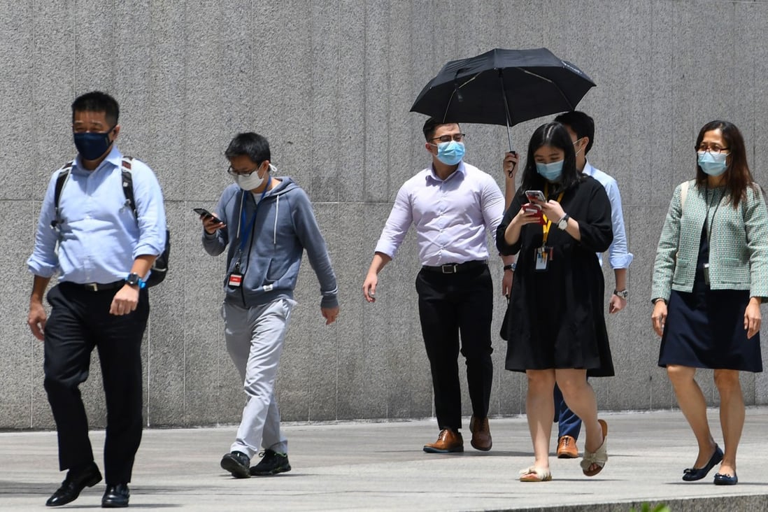 Singapore workers are seen outside their office building during their lunch break, after people returned to their workplaces as Covid-19 restrictions were eased. Photo: AFP