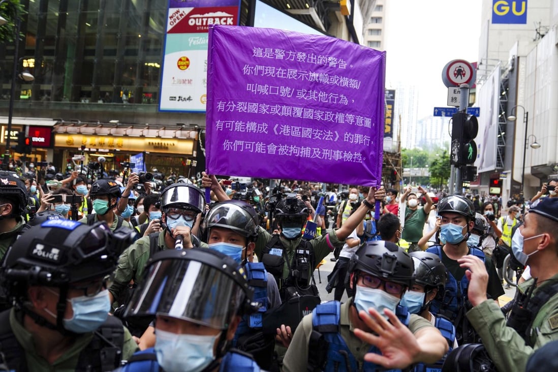 Police officer raised up a purple flag warning protesters they are in violation of the national security law during a gathering in Causeway Bay on October 1, 2020. Photo: Sam Tsang