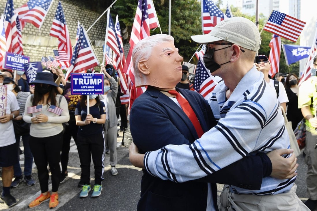 A protester embraces another wearing a Donald Trump mask during a pro-US rally in Central on December 1, 2019, after the American president signed the Hong Kong Human Rights and Democracy Act. Photo: Kyodo