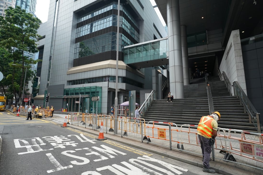 A worker on Monday replaces the street-side railing in front of police headquarters in Wan Chai after removing water-filled barricades there. Photo: Felix Wong