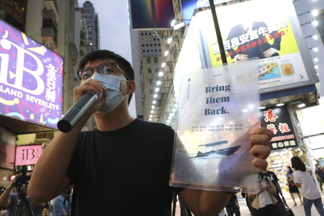 Opposition activist Joshua Wong holds up a small poster calling for the return of a dozen Hong Kong fugitives being held in mainland China. Photo: Dickson Lee